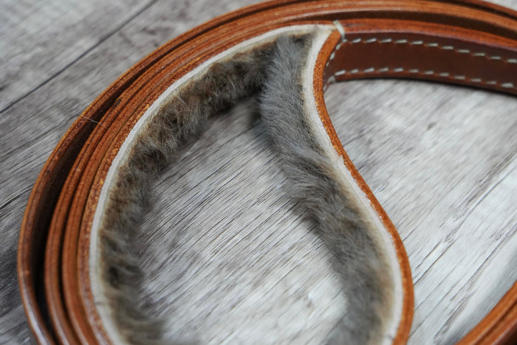 Brown leather lead with gold buckle on a wooden surface